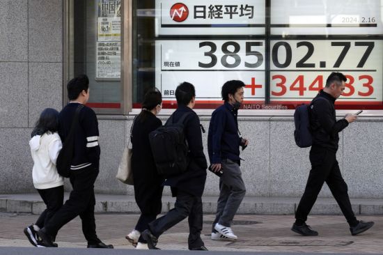 16일 일본 도쿄 시내에서 행인들이 증시 현황판 앞을 지나가고 있다. [이미지출처=연합뉴스]