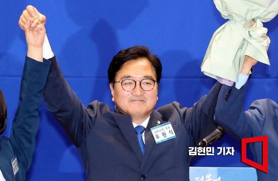 더불어민주당 국회의장 후보로 선출된 우원식 후보가 16일 국회 의원회관에서 열린 제22대 전반기 국회의장단 후보 선출을 위한 당선자 총회에서 꽃다발을 들고 두 팔을 들어 올리고 있다. 사진=김현민 기자 kimhyun81@