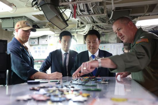 윤석열 대통령이 25일 부산 해군작전기지에서 미 해군 항공모함 시어도어 루즈벨트함에 승선해 비행갑판 통제실에서 브라이언 스크럼 루즈벨트 함장으로부터 항모에 대한 설명을 듣고 있다. [이미지출처=연합뉴스]