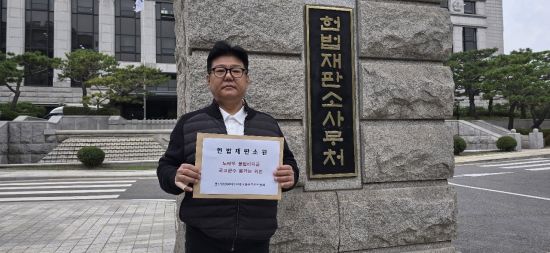 군사정권범죄수익 국고환수추진위원회 김근호 사무국장이 지난달 1일 오후 서울 종로구 재동 헌법재판소 앞에서 헌법소원심판 청구서를 들고 있는 모습. 군사정권범죄수익 국고환수추진위원회 제공