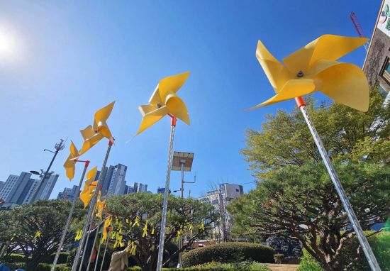 세월호 참사 11주기를 아흐레 앞둔 7일 광주 북구청 광장에서 구청 인권교육과 직원들이 광장 화단에 바람개비와 노란 리본 등을 설치하고 있다. 광주 북구 제공 연합뉴스