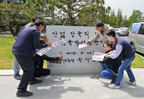 민주노총 경남본부가 한국산업단지공단 경남지역본부 앞마당에서 윤 전 대통령 친필 휘호 표지석을 부수는 듯한 항의행동을 하고 있다. 이세령 기자