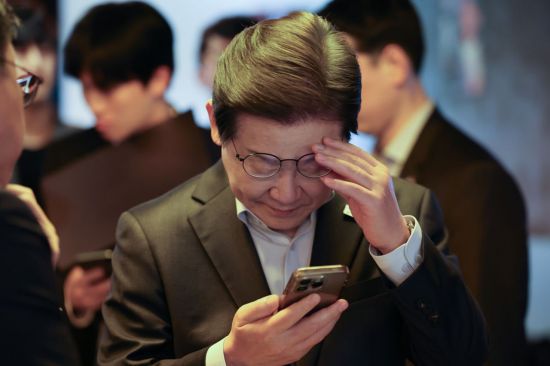 이재명 더불어민주당 대선 후보가 지난 1일 서울 서울 종로구의 한 포차 식당에서 비(非)전형 노동자들과의 간담회를 마친 뒤 자신의 재판 결과를 확인하고 있다. 국회사진기자단 연합뉴스