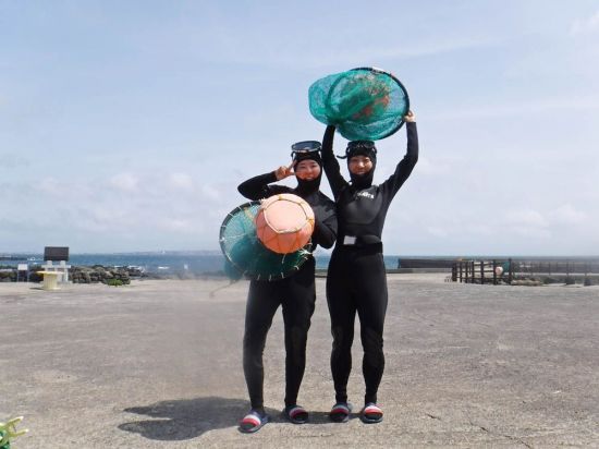 태왁과 망사리를 들고 기념 사진을 찍는 관광객