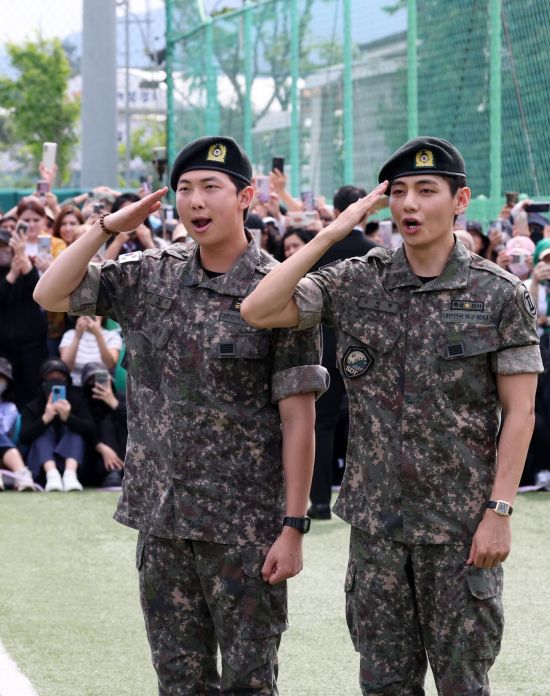 그룹 방탄소년단(BTS) 멤버 뷔와 RM이 10일 강원 춘천시 신북읍 체육공원에서 열린 전역 기념행사에서 팬과 취재진을 향해 경례하고 있다. 연합뉴스