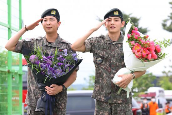 육군 현역 복무를 마치고 만기 전역한 그룹 방탄소년단(BTS) RM과 뷔가 10일 강원 춘천시 신북읍체육공원에서 취재진을 향해 거수경례하고 있다. 연합뉴스