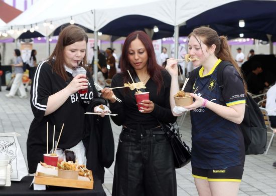 외국인 관광객들이 '2025 마이케이 페스타' 현장에서 K푸드를 먹고 있다.   [사진 제공= 문화체육관광부]