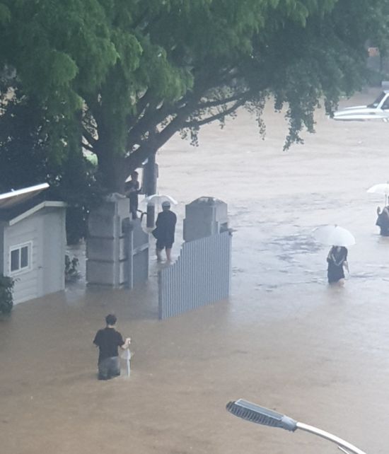무릎 높이까지 찬 물속을 걸어 나오는 시민들. 18일 오후 광주의 한 주택가 일대가 폭우로 잠기면서 주민들이 우산을 들고 물을 헤치며 이동하고 있다. 엑스 갈무리