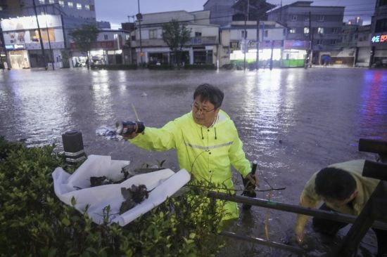 강기정 광주시장이 17일 오후 폭우로 침수된 북구 신안교 일대를 돌며 배수로를 막은 플라스틱, 비닐 등의 쓰레기를 직접 치우고 배수 상황을 점검하고 있다. 광주시 제공