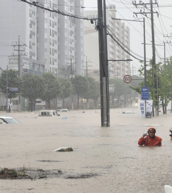 차량들만 둥둥 떠다닌다. 18일 오후 광주 북구 신안동 한 도로가 폭우로 완전히 잠겨 구조대원이 허리까지 찬 물을 헤치며 수색에 나서고 있다. 엑스 갈무리