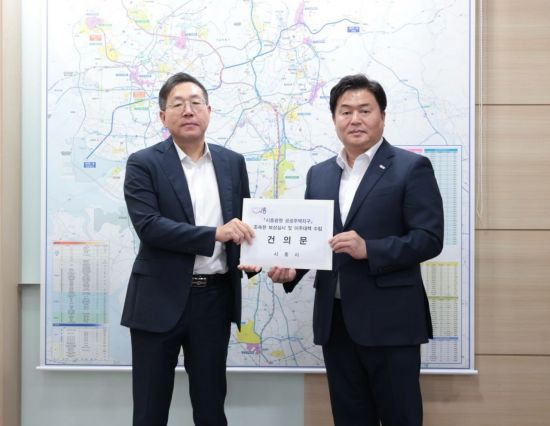 임병택 시흥시장(오른쪽)이  최용택 한국토지주택공사(LH) 광명시흥사업본부장에게 주민들의 요구를 담은 건의문을 전달하고 있다. 시흥시 제공