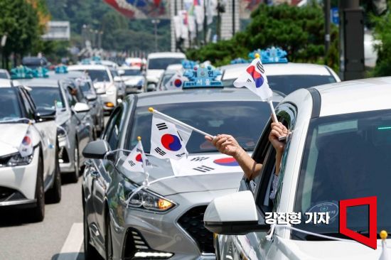 지난해 광복절을 이틀 앞두고 서울 송파구 올림픽로에서 태극기로 장식한 택시를 탑승한 독립유공자 가족이 태극기를 흔들고 있다. 강진형 기자