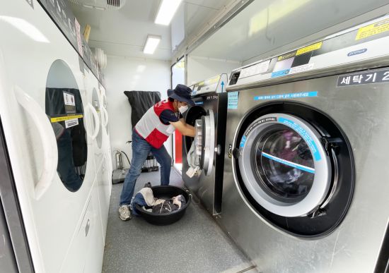 희망브리지 자원봉사자가 이동식 세탁구호차량 내부에서 수거한 세탁물을 세탁하고 있다. 희망브리지