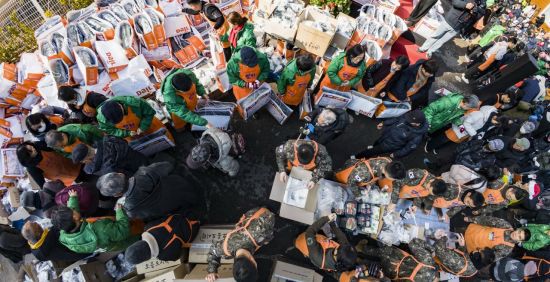 크리스마스를 하루 앞둔 지난 24일 서울 동대문구 밥퍼나눔운동본부에서 열린 거리 성탄 예배에서 자원봉사자들이 참가자들에게 음식과 생필품 등을 전달하고 있다. 공동취재단