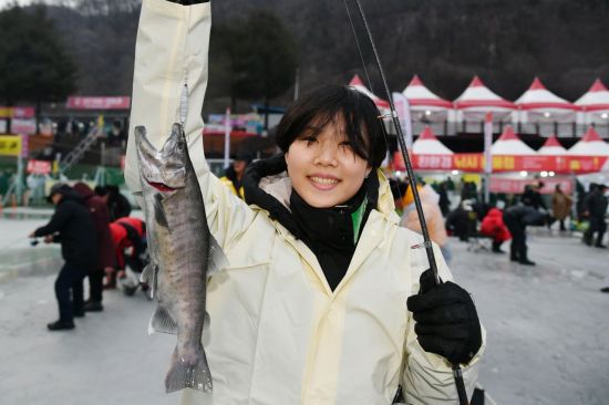 10일 개막한 2026 화천산천어축제 현장을 찾은 한 여성 관광객이 낚시로 잡은 산천어를 들어보이고 있다. 화천군 제공