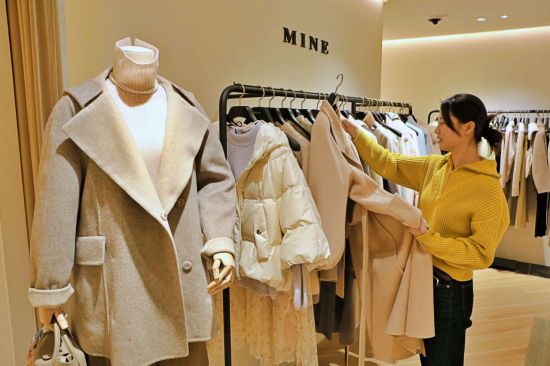 고객이 여성 의류 매장에서 겨울 아우터 상품을 둘러보는 모습.