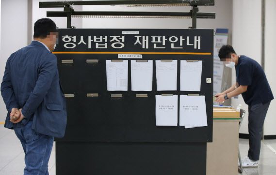 신종 코로나 바이러스 감염증(코로나19) 확산세로 24일부터 다음 달 4일까지 임시 휴정기에 돌입한 서울 서초구 서울중앙지법에 한 시민이 재판안내 게시판을 살펴보고 있다. (사진=연합뉴스)