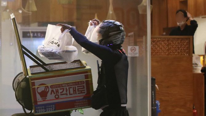 신종 코로나바이러스 감염증(코로나19) 확산 방지를 위해 수도권 지역의 사회적 거리두기 2.5단계가 시행된 30일 오후 9시 이후 서울 송파구의 한 음식점 앞에서 한 배달기사가 포장 음식을 나르고 있다. (사진=뉴시스)