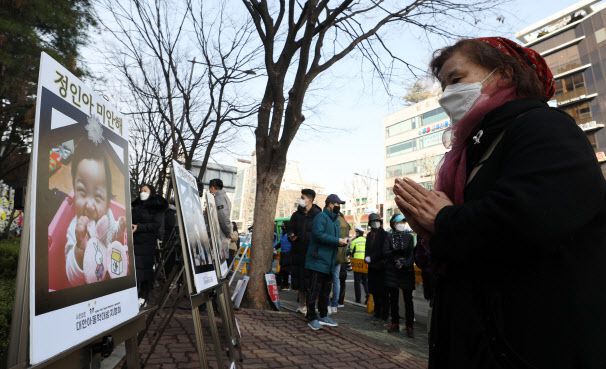 16개월 여아 ‘정인이’의 입양부모 5차 공판이 열리는 3일 서울 양천구 서울남부지방법원 앞에서 한 시민이 정인이 사진을 보며 기도하고 있다. (사진=뉴시스)