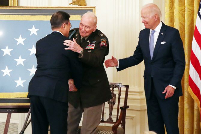 문재인 대통령이 21일 오후(현지시간) 미국 워싱턴 백악관 이스트룸에서 열린 한국전쟁 명예 훈장 수여식에 참석해 랠프 퍼킷 주니어 퇴역 대령과 포옹을 하고 있다. 오른쪽은 조 바이든 미국 대통령.(사진=뉴시스)