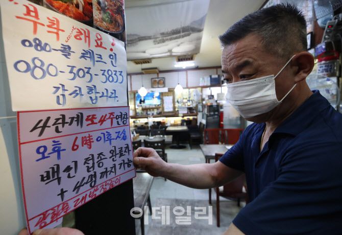 방역수칙 일부 완화가 포함된 현행 사회적 거리두기가 4주 연장 시행된 지난 6일 서울 종로구의 한 식당에서 주인이 안내문을 붙이고 있다. (사진=뉴스1)