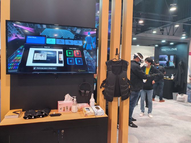 지난 7일(현지시간) 폐막한 세계 최대 IT 가전 전시회 ‘CES 2022’에 꾸려진 국내 VR업체 비햅틱스의 전시부스. 메타버스 속 촉각을 구현한 햅틱조끼와 햅틱장갑 등이 전시돼 있고, 관람객들이 이를 체험하고 있다. (사진=김정유 기자)