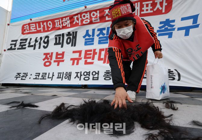 [이데일리 노진환 기자] 코로나피해자영업총연합이 15일 서울 광화문 열린마당에서 집합제한 철폐 및 손실보상 촉구 정부 규탄대회를 개최한 가운데 관계자가 삭발식 후 쌓인 자영업자들의 머리카락을 치우고 있다.