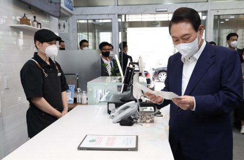윤석열 대통령이 18일 오후 서울 강남구 역삼동 충현복지관을 방문, 주문한 음료를 기다리며 발달장애인 예술작가가 그린 엽서를 보고 있다.(사진=연합뉴스)
