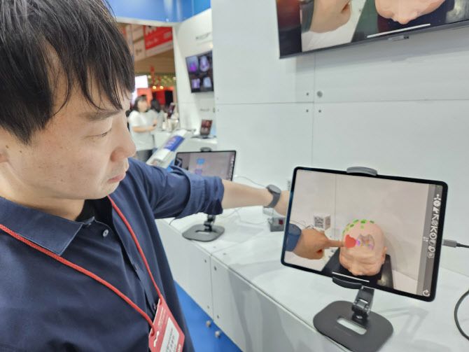 메디컬아이피 관계자가 의료 수술 시뮬레이션 등에 사용되는 자사 XR솔루션을 설명하고 있다. 손으로 지목하고 있는 곳이 가상의 종양이다. (사진=김정유 기자)