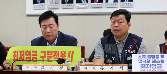 22일 오후 세종시 정부세종청사 최저임금위원회 회의실에서 열린 제7차 전원회의에서 근로자위원인 류기섭 한국노총 사무총장(오른쪽)이 발언을 시작하자 류기정 한국경영자총협회 전무(왼쪽)을 비롯한 사용자위원들이 최저임금 구분적용 필요성을 강조하는 손팻말을 들어 보이고 있다.(사진=연합뉴스)
