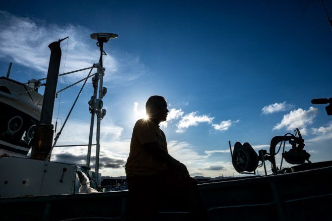 24일부터 원전 오염수를 방류하는 후쿠시마 제1원전에서 북쪽으로 약 60km 떨어진 후쿠시마현 신치마치 쓰루시하마 어항에서 한 일본 어부가 어선에 앉아있다. (사진=AFP)