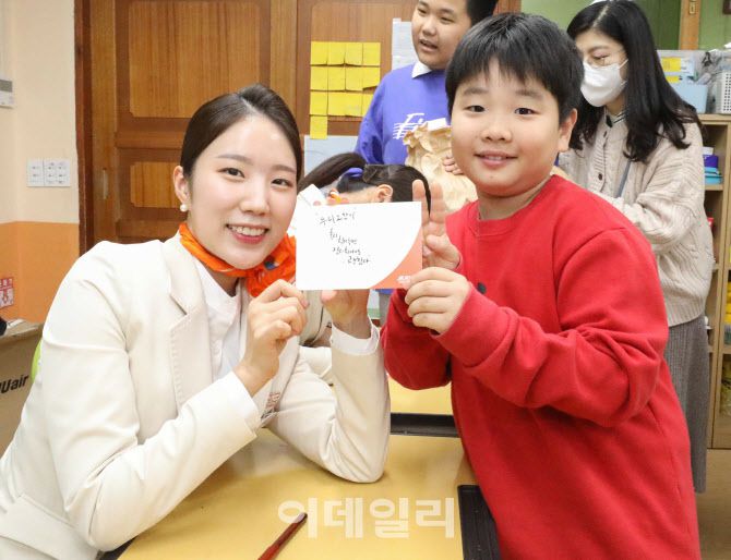 제주항공 객실승무원이 경기도 용인 고기초등학교에서  어린이에게 응원의 메시지를 담은 캘리그래피를 선물하고 있다.(사진=제주항공)