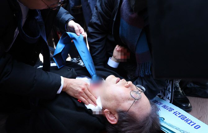 이재명 더불어민주당 대표가 2일 부산 가덕도 신공항 부지를 둘러본 후 기자들과 문답을 진행하던 중 왼쪽 목 부위에 습격을 당해 피를 흘린 채 쓰러져 있다.(사진=연합뉴스)