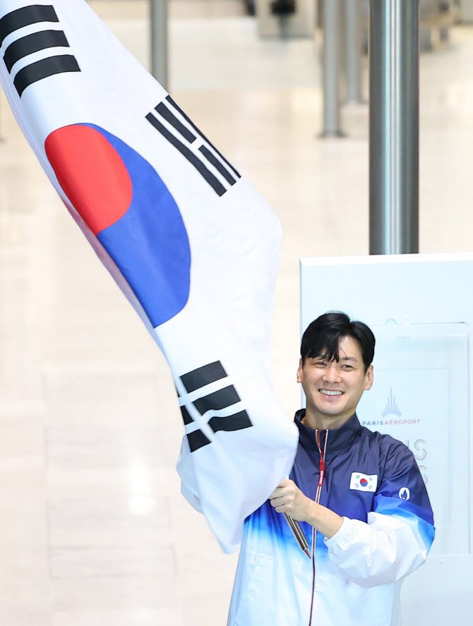2024 파리올림픽에 출전하는 구본길이 20일 오후(현지시간) 프랑스 파리 샤를 드골공항 2터미널에서 태극기를 흔들어보이고 있다.(사진=연합뉴스)