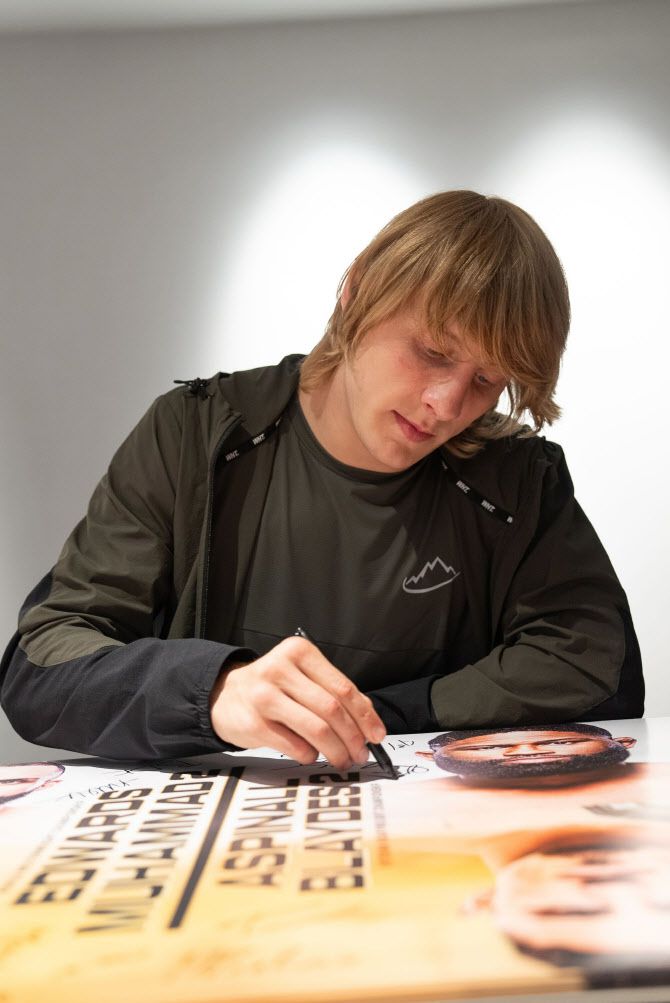 자신의 얼굴이 담긴 대회 포스터에 사인을 하고 있는 패디 핌블렛. 사진=UFC