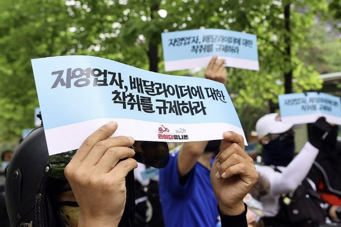 민주노총 공공운수노조 라이더유니온지부 조합원들이 21일 오후 국회의사당 역 앞에서 ‘배달라이더 × 배달상점주 플랫폼 갑질 규탄대회’를 열고 구호를 외치며 피켓을 올리고 있다. (사진=연합뉴스)