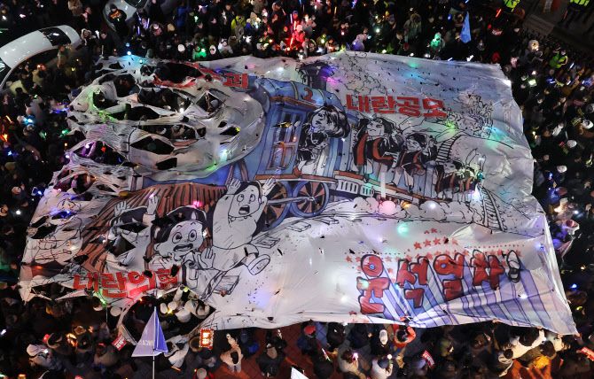 ‘윤석열 즉각 퇴진·사회대개혁 비상행동’ 주최로 13일 오후 서울 영등포구 국회의사당 인근에서 열린 탄핵소추안 국회 통과 촉구 촛불집회 참가자들이 국민의힘 당사 앞까지 행진해 현수막을 찢는 퍼포먼스를 펼치고 있다 (사진=연합뉴스)