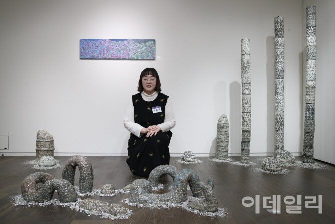 곽재선문화재단 ‘제3회 아트공모전’에서 대상을 수상한 작가 김민지가 수상작 ‘탈피’(2022, 120×70×45㎝) 뒤에 앉았다. 작가 뒤 오른쪽으로 조각작품 ‘성장통’(2021∼2022, 11×11×160∼200㎝)이, 왼쪽으로 부조작품 ‘줄기’(2024, 27×35㎝ 3점)가 보인다(사진=이영훈 기자).