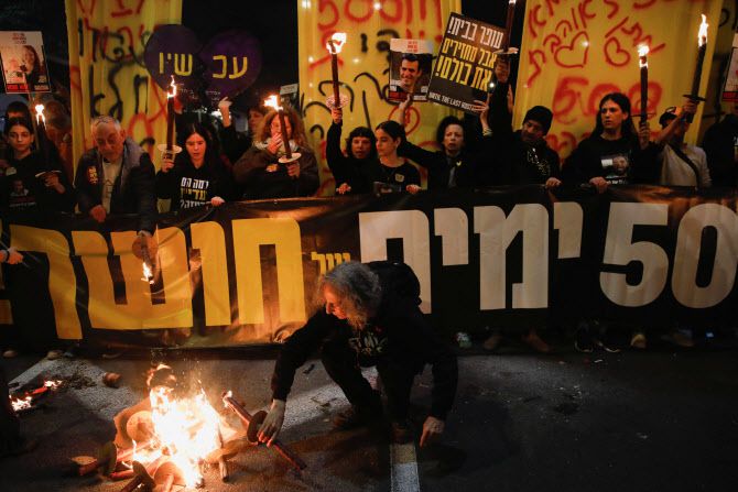 17일(현지시간) 이스라엘 텔아비브에서 2023년 10월 7일 하마스가 이스라엘을 공격해 인질을 납치한 지 500일을 맞아 인질 가족과 지지자들이 시위를 벌이는 가운데 불이 타오르고 있다. (사진=로이터)