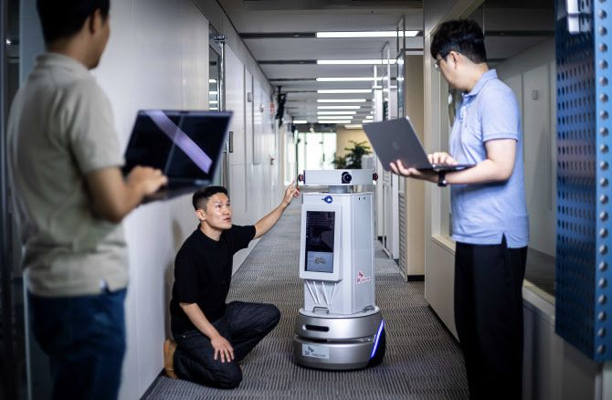 SK텔레콤 직원들이 ‘텔코 에지 AI’ 기반 자율주행 로봇 기술을 실증하고 있다. (사진=SK텔레콤)