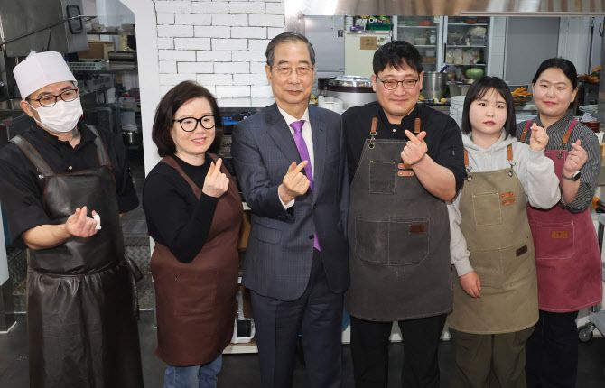 한덕수 대통령 권한대행 국무총리가 16일 결식 아동들에게 무료 점심을 제공해온 울산 뚠뚠이 돈가스에서 사장과 직원들을 격려하고 기념사진을 촬영하고 있다.(사진=연합뉴스 제공)