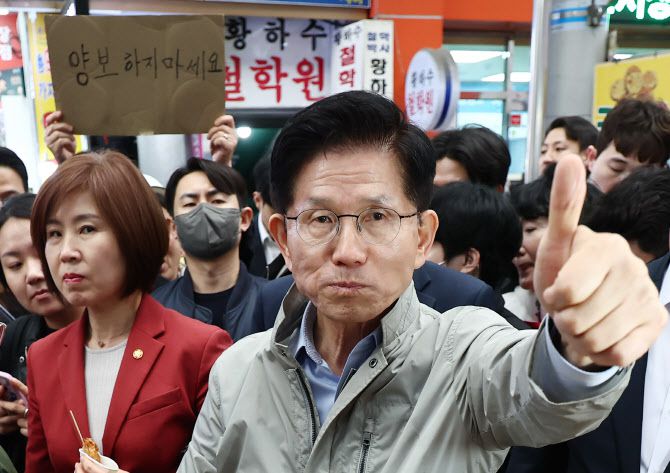 김문수 국민의힘 대선 후보가 6일 경북 포항시 죽도시장에서 구매한 어묵을 먹으며 엄지를 치켜세우고 있다. 뒷편으로는 한 지지자가 ‘양보 하지 마세요’라고 적힌 종이를 들어보이고 있다 (사진=뉴스1)