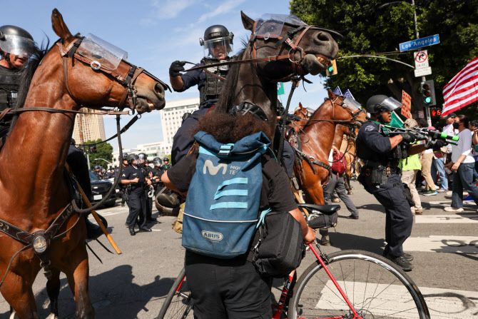 14일(현지시간) 로스앤젤레스 도심의 연방청사 앞에서 반(反)트럼프 ‘노 킹스 데이(No Kings Day)’ 시위에 참가한 시위대가 경찰과 대치하고 있다.(사진=AFP)