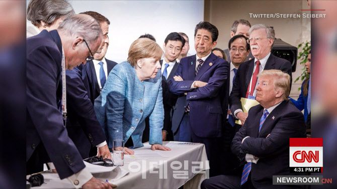 2018년 6월 캐나다에서 열린 주요7개국(G7) 정상회의 당시 앙겔라 메르켈 전 독일 총리가 탁자를 짚고 팔짱을 끼고 있는 도널드 트럼프 미국 대통령과 마주보고 있다. (사진=CNN방송 캡처)