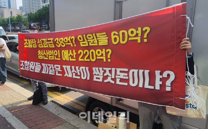 평촌 어바인스트 조합원들이 조합장과 임원들 성과급 지급을 반대하는 현수막을 들고 시위하고 있다.(사진=제보자)