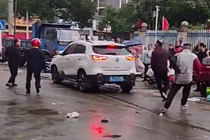 19일 중국 소셜미디어에 유포된 영상에서 흰색 차량이 초등학교 앞 행인을 지나가고 있다. 해당 차는 중국 후난성 창더현의 한 초등학교 앞 등굣길 학생과 학부모를 차로 친 것으로 알려졌다. (사진=AFP)