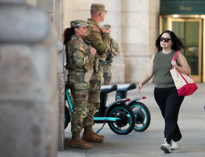 25일(현지시간) 미국 워싱턴DC의 유니온 스테이션에서 한 여행객이 무장한 주방위군 옆을 지나가고 있다. (사진=AFP)