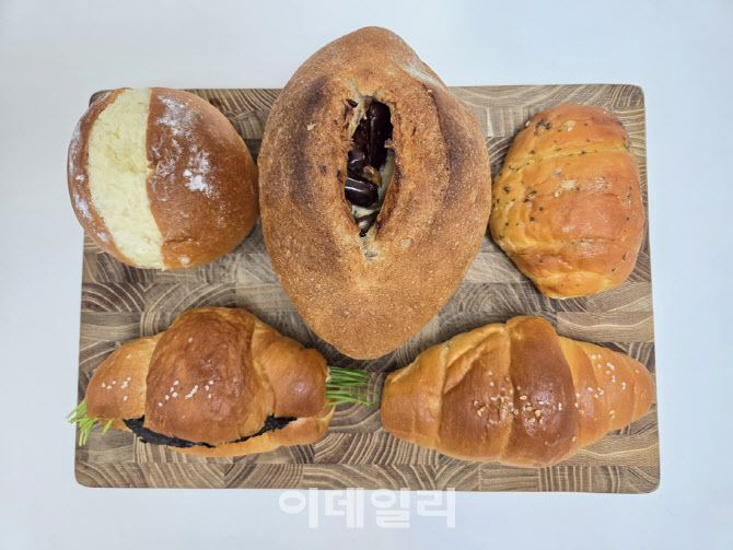 도마 위에 담긴 ETF 베이커리 빵 5종. 왼쪽 위부터 시계방향으로 쌀크림빵, 대추 무화과 깜빠뉴, 마늘버터 소금빵, 소금빵, 부추 명란 소금빵. (사진=한전진 기자)