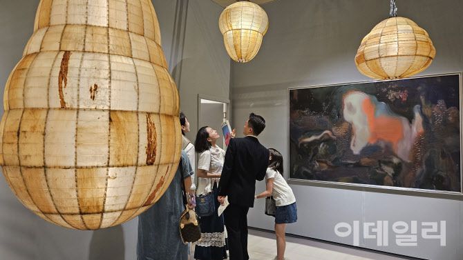 ‘프리즈 서울 2025’ 전경. 가족으로 보이는 관람객이 글래드스톤 부스에 걸리고 매달린 아니카 리의 조각·회화작품들을 둘러보며 즐거워하고 있다(사진=오현주 문화전문기자).