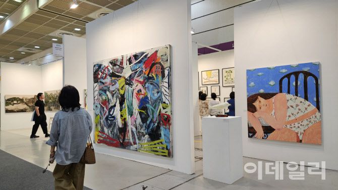 ‘키아프 서울 2025’ 전경. 한 관람객이 야리라거갤러리에 걸린 갈리나 먼로의 회화작품(오른쪽), 로즈 와일리의 조각·판화작품 등을 바라보며 이동하고 있다(사진=오현주 문화전문기자).